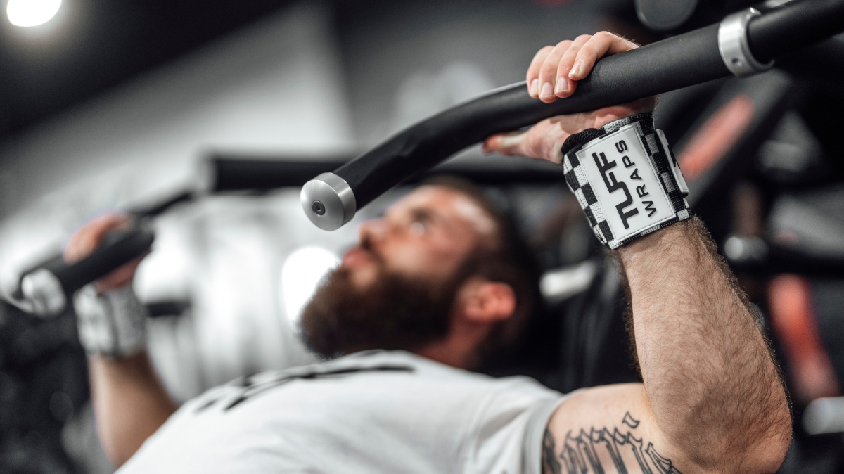 Lifter wearing wrist wraps grips a barbell during bench press to avoid wrist pain