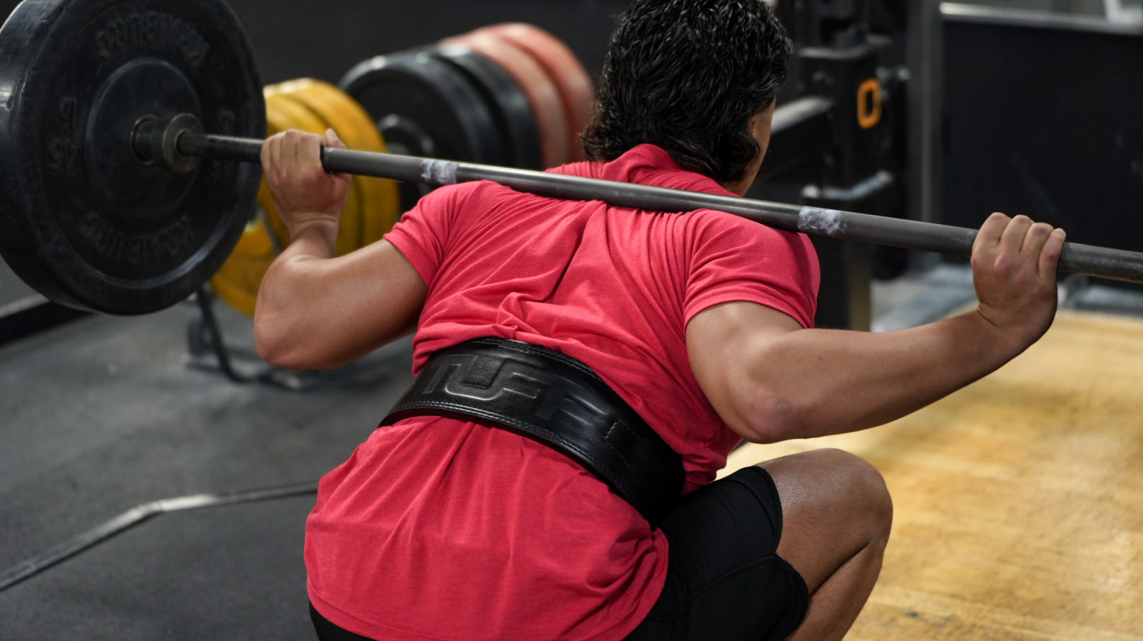 trainer squatting with lifting belt