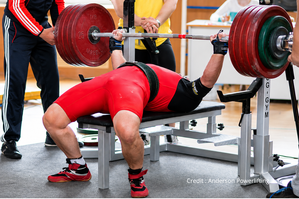 Lifter wearing wrist wraps and a lifting belt loading a barbell, illustrating an Anderson Powerlifting review