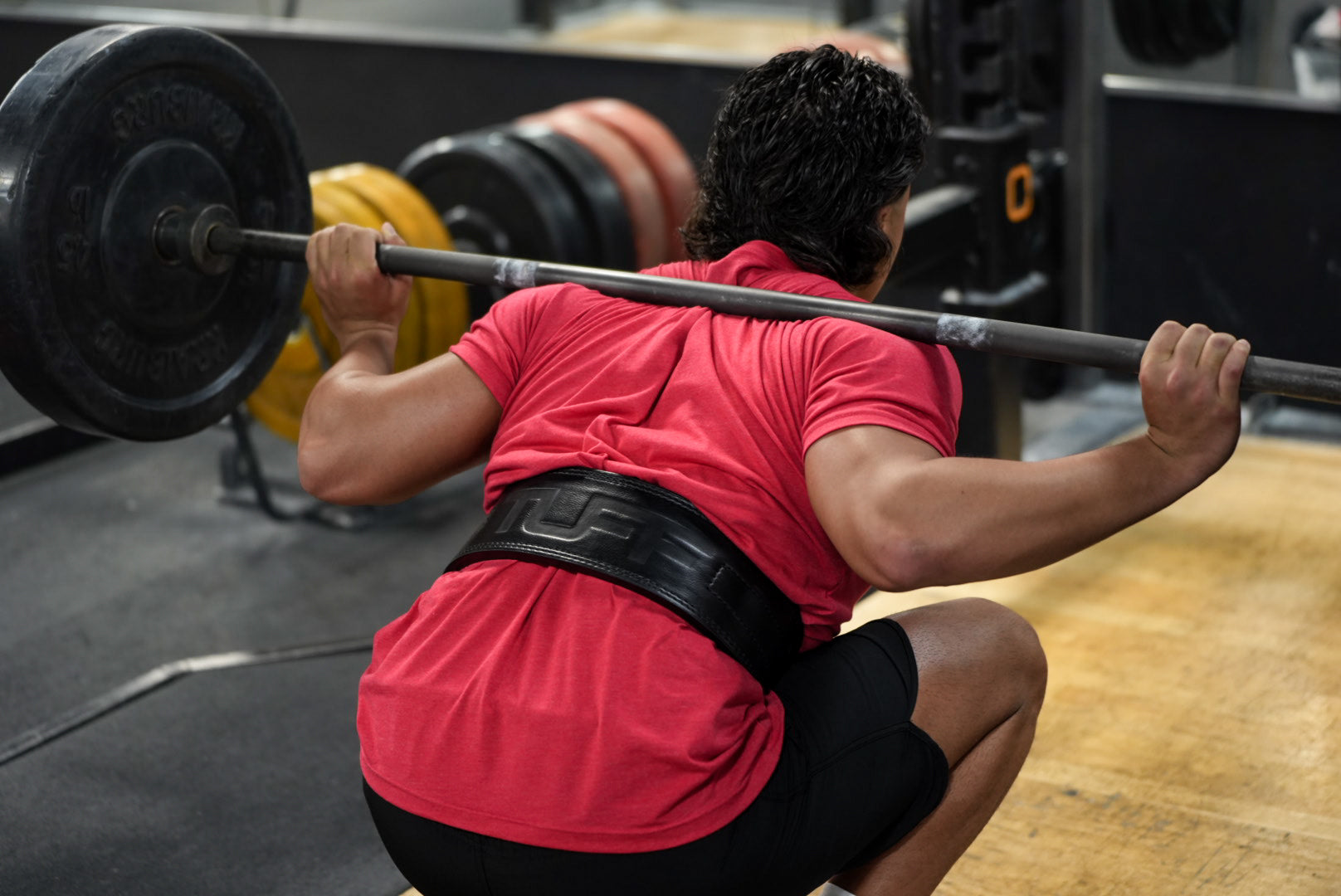trainer squatting with lifting belt